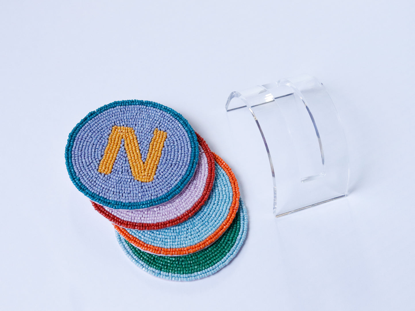 Set of colorful beaded coasters with a letter 'N' on a light blue background