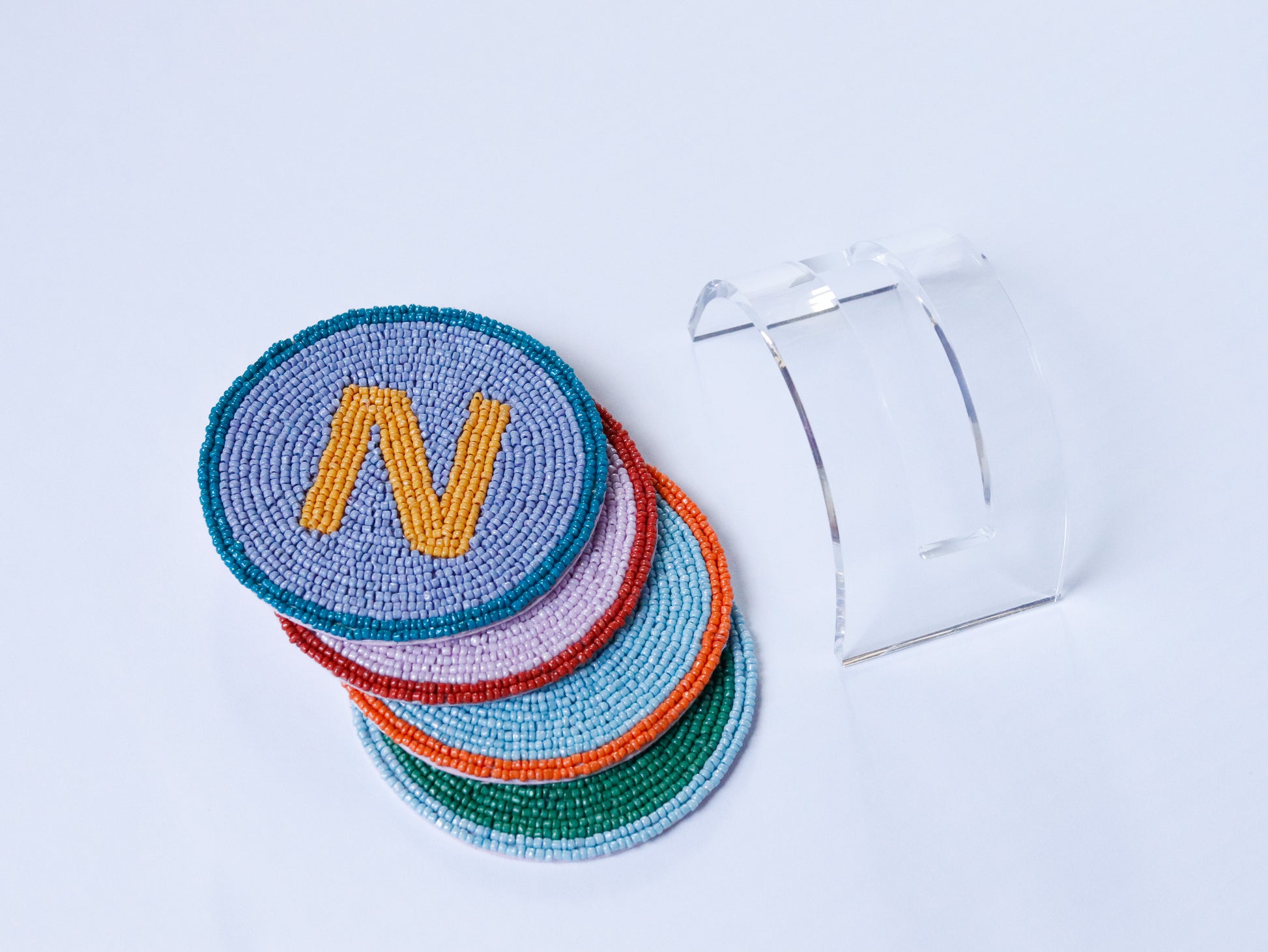 Set of colorful beaded coasters with a letter 'N' on a light blue background